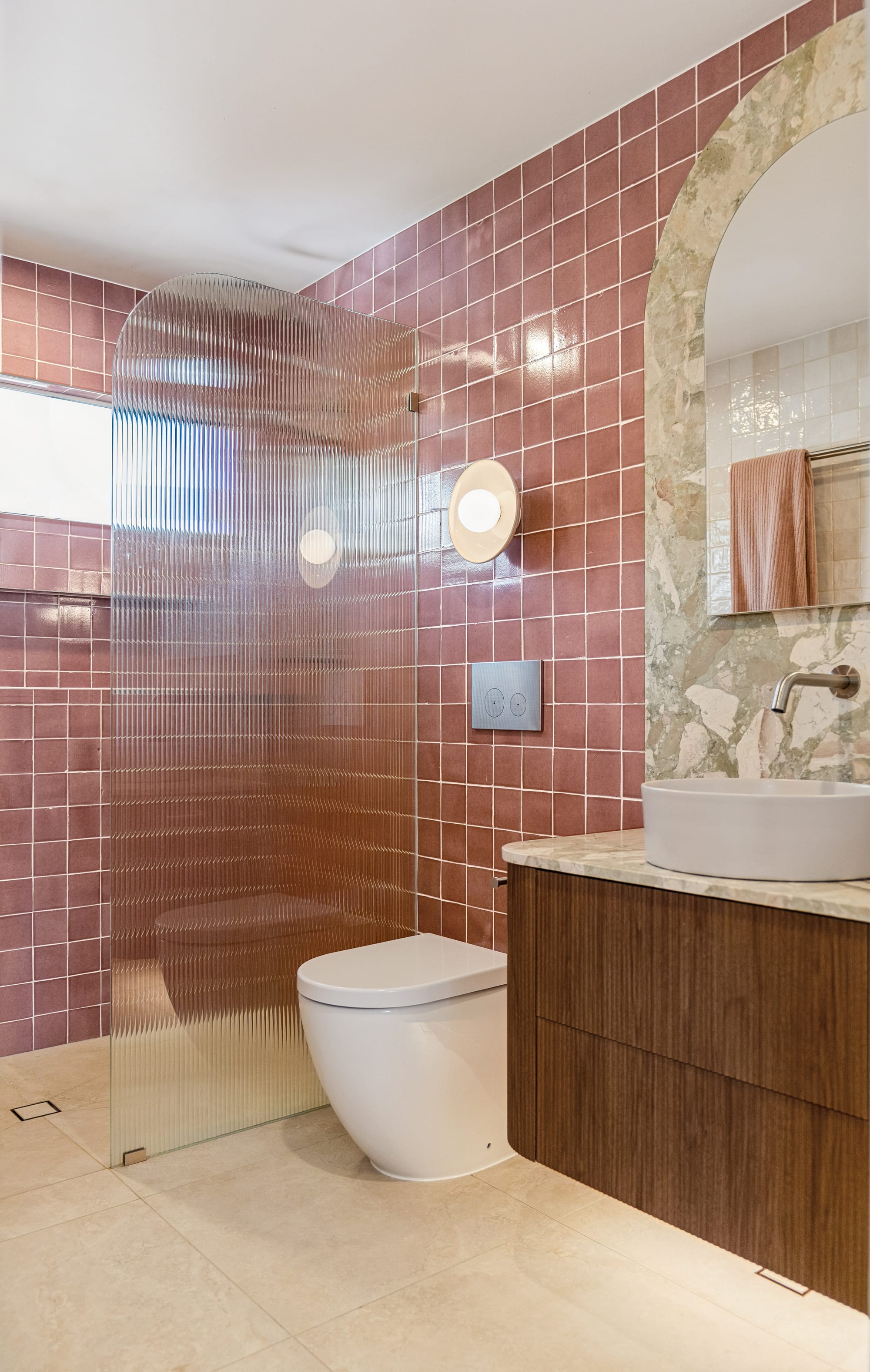 Chardonnay Court House by Studio MDM. Photography by Focl Media. Bathroom with pink wall tiles, fluted glass shower screen and fluted timber floating cabinet. 