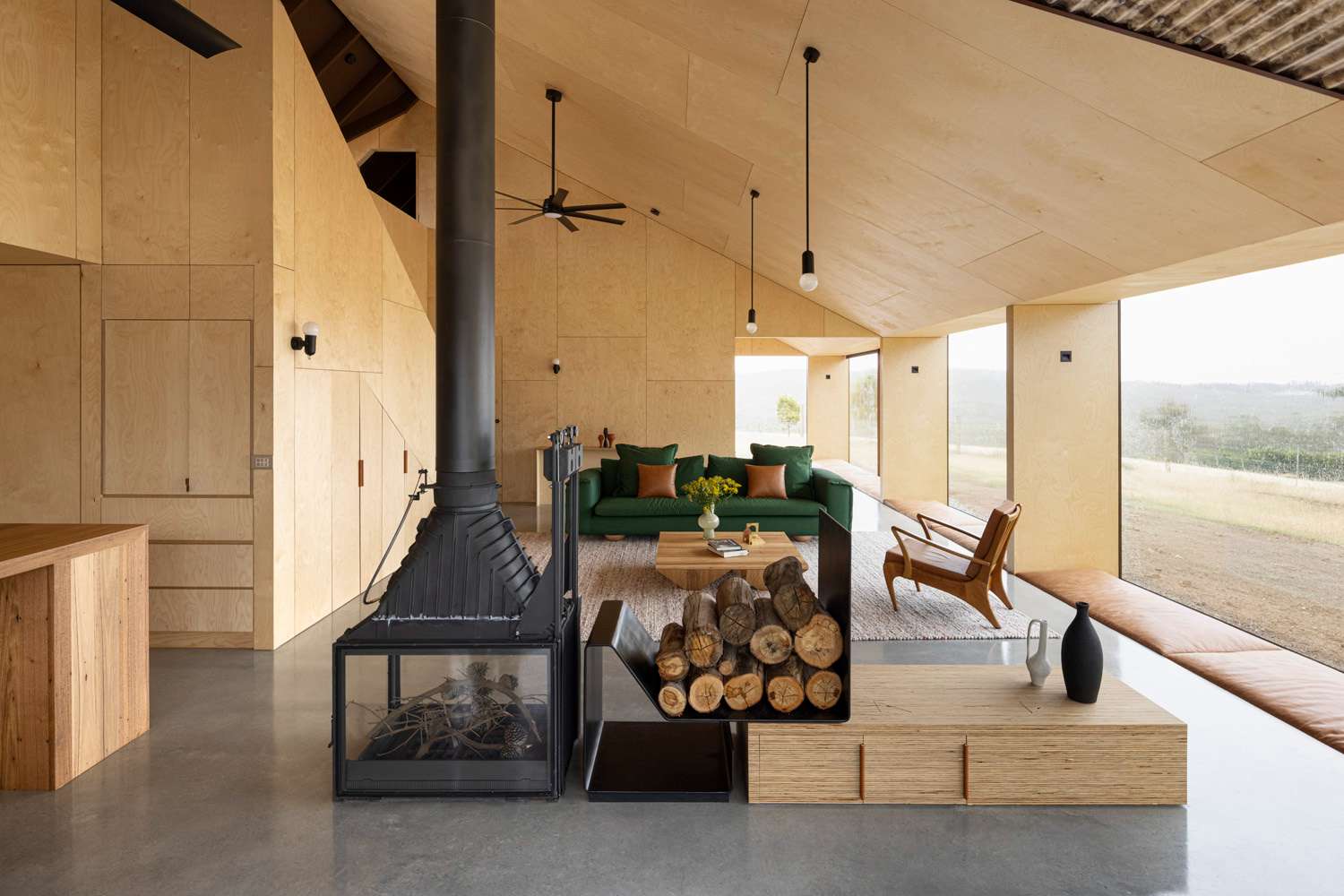An interior shot of the living space with plywood lined walls and ceiling and a feature fireplace.