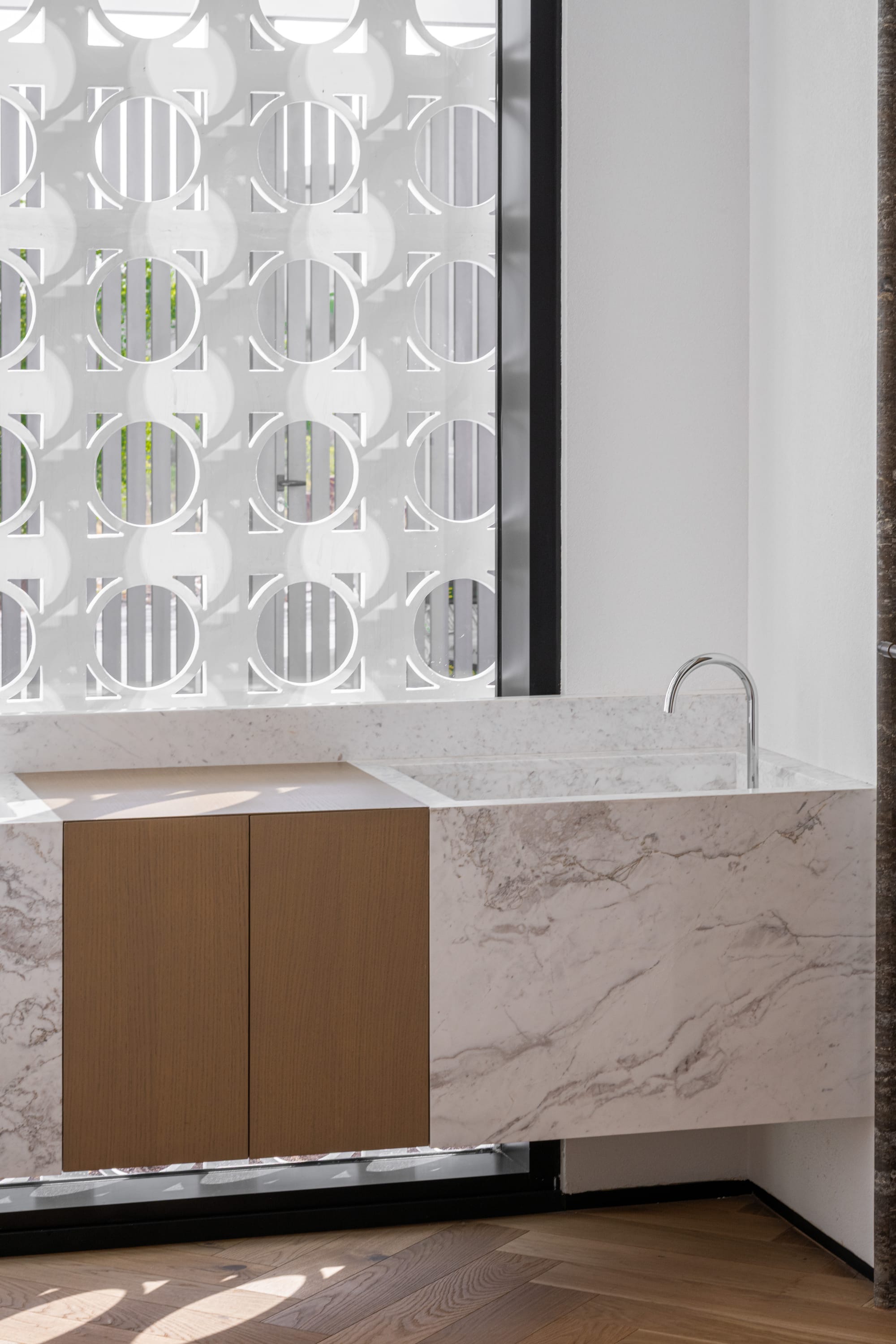 Veil House by ENCLAVE Architects. Photography by Hassan Arante & Gener Rayes. Bathroom with floating stone basin and counters, herringbone timber floors and window with circular pattern screening.