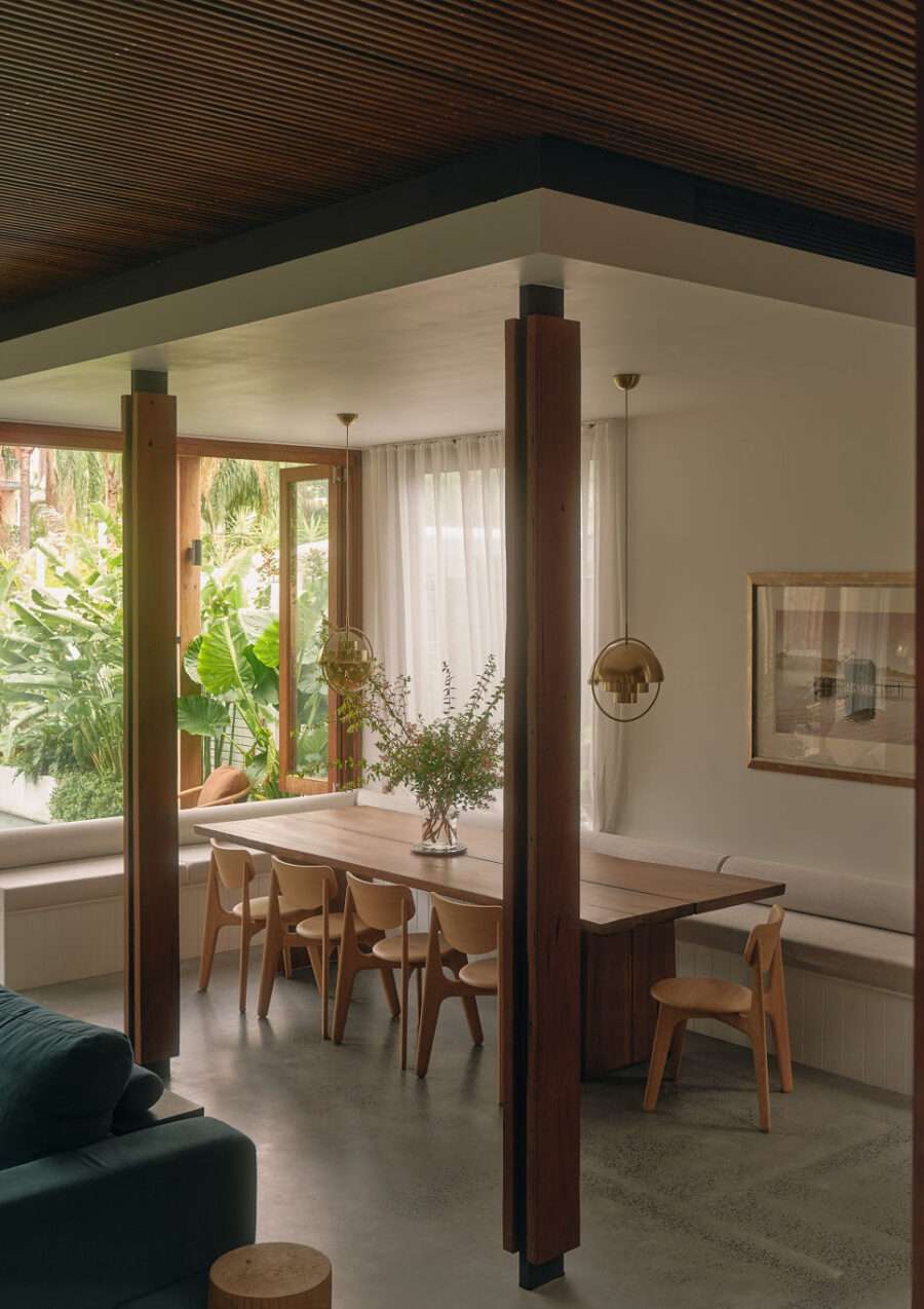A stylish dining room with a large timber table, polished concrete floor and designer pendants over.