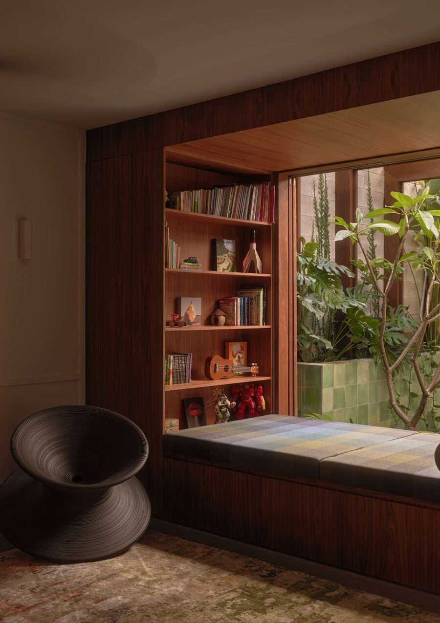 A shot of a window seat looking out to a garden courtyard with a book case which makes for the perfect place to read.