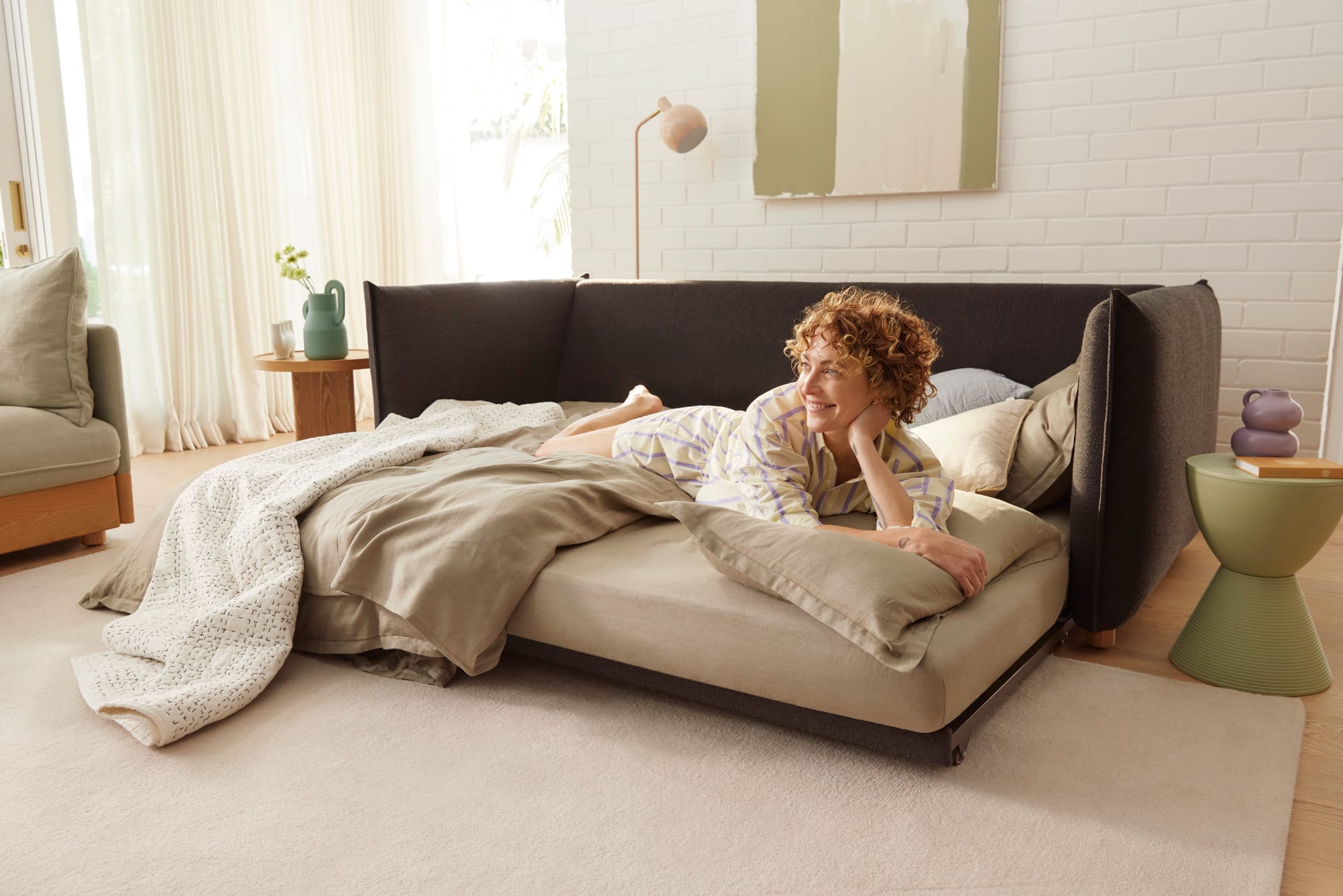 Koala's Byron Bay Sofa Bed in Currawong Grey with woman laying on the sofa bed.