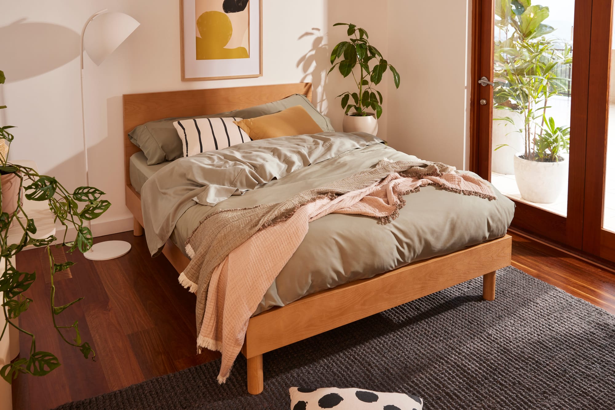 Koala Balmain Bed Base. Timber bed frame with sage green linen in bedroom with timber flooring and a grey rug.
