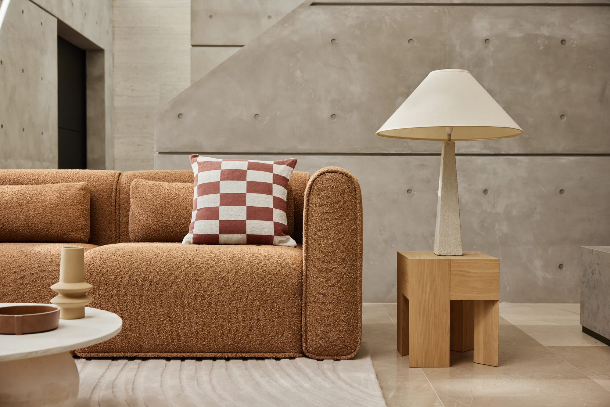 Bangalow Modular Sofa in Sand Dune. Living space with brown couch, concrete walls, and tiled floors.