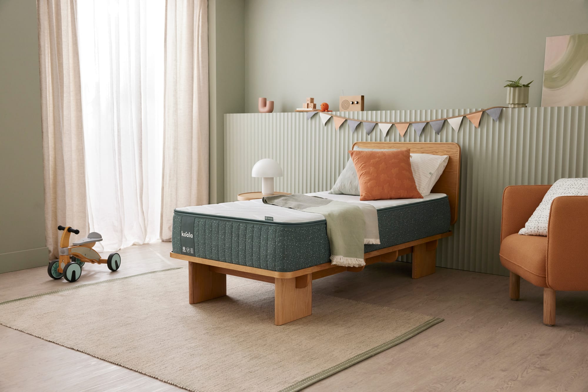 Koala Polar+ Mattress. Childs bedroom with green walls, bunting and a timber bedframe with a white and green mattress.