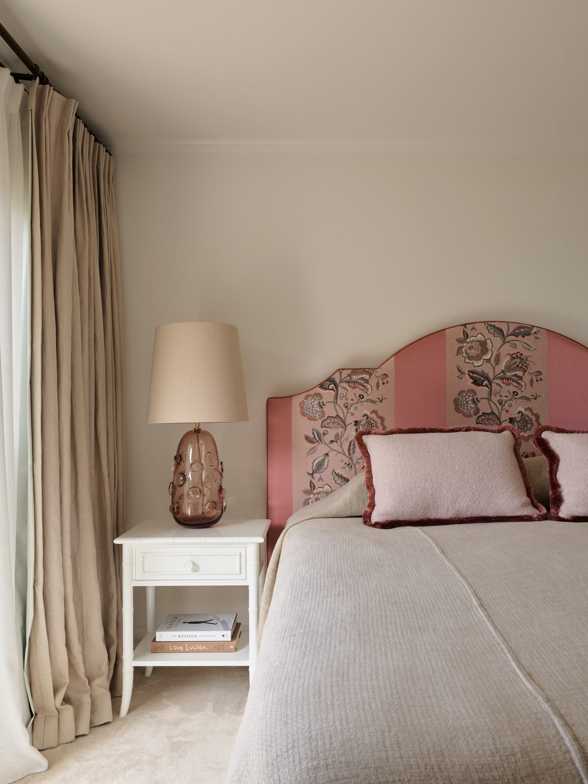 The Darling Edit by Marylou Sobel Interior Design. Photography by Anson Smart. Bedroom with pink patterned fabric headboard, white side table, abstract pink bedside table lamp and pink cushions.