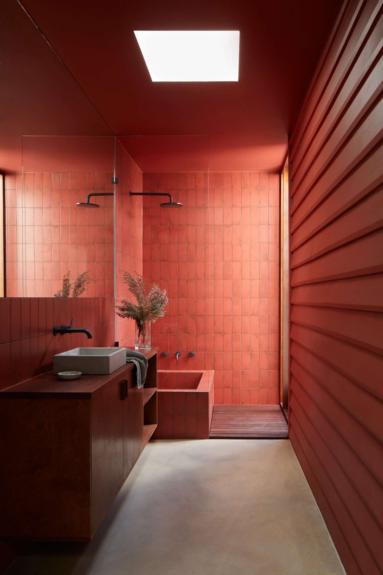 An interior shot of the bathroom with red tiles and a timber vanity.