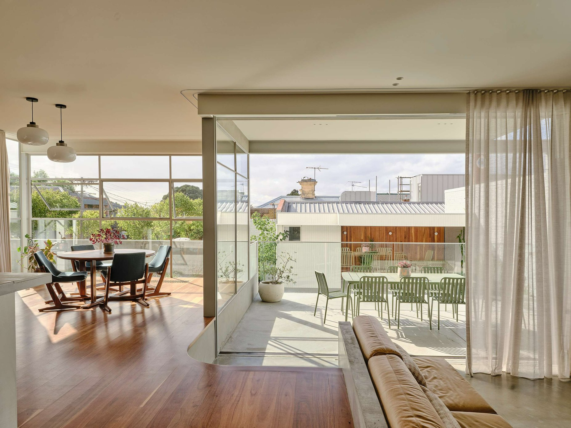 Salmon House by True Story. Photography by Dean Bradley. Open plan dining and living space with full height windows, and full height doors opening onto balcony. 
