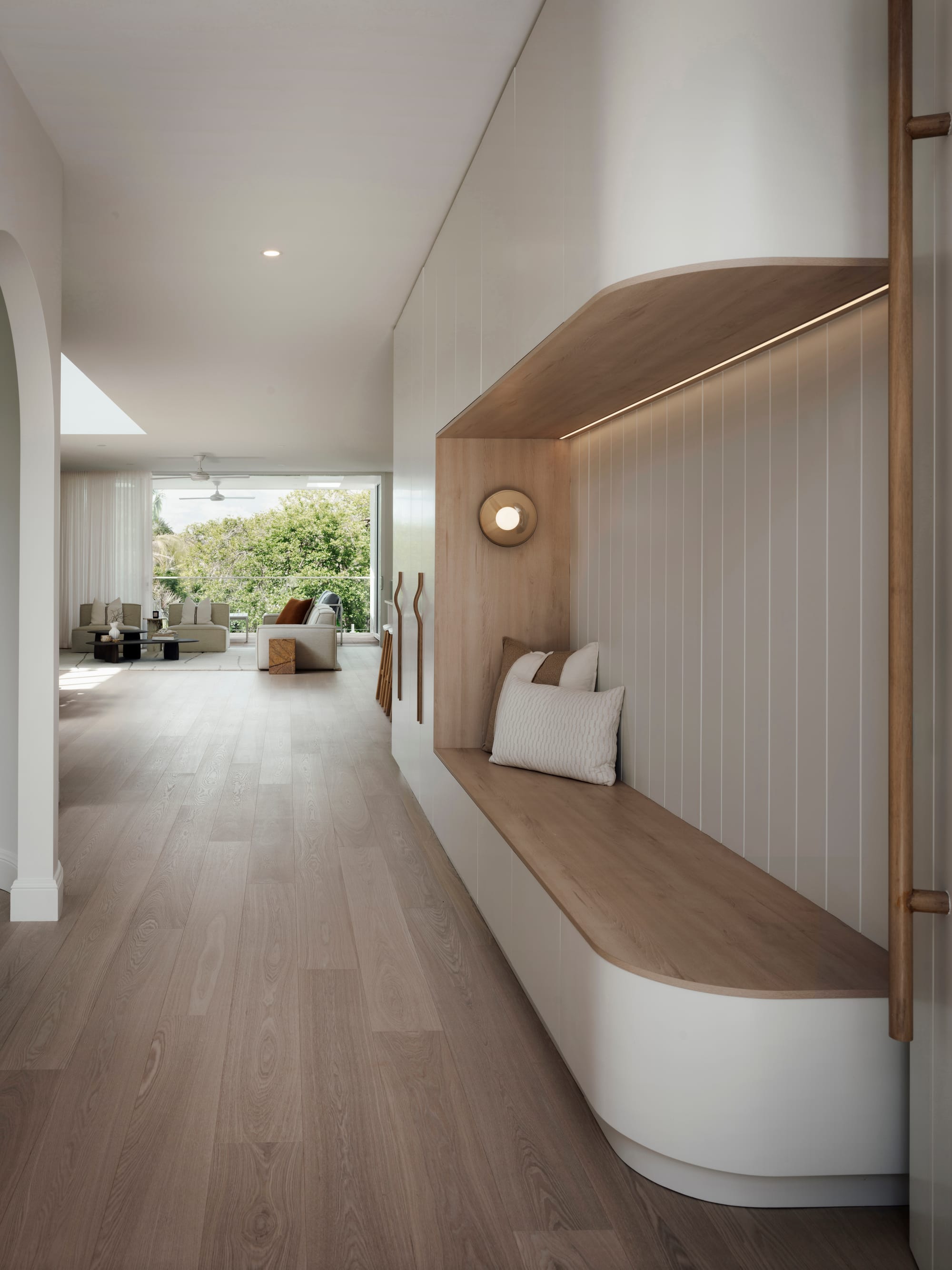 Sienna House by 868 Architects. Photography by Luke Butterly. Hallway and entry with timber flooring, timber bench seating, white cabinetry and walls. 