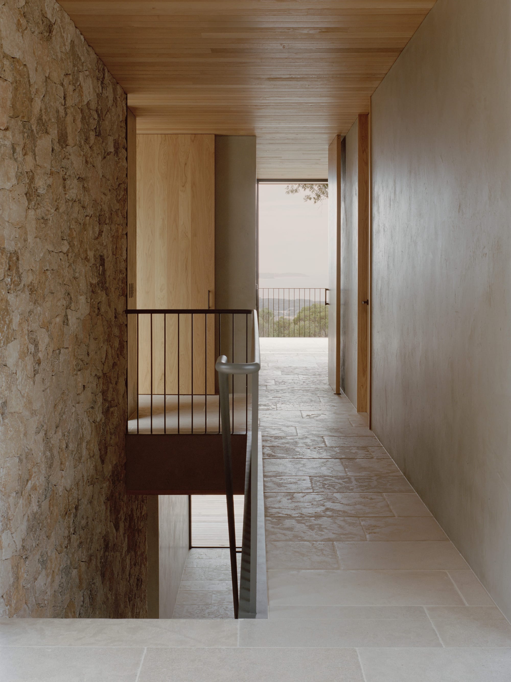Anglesea House by Eckersley Architects. Photography by Tasha Tylee. Upstairs hallway with stone paver flooring, lime-washed walls, timber clad ceiling and timber doorframes.