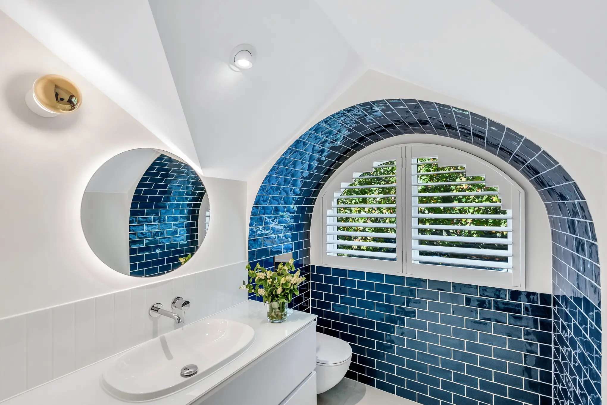 Cozy Elegance by Emotive Designs. Bathroom with blue subway wall tiles, arched ceiling and window and white walls. 