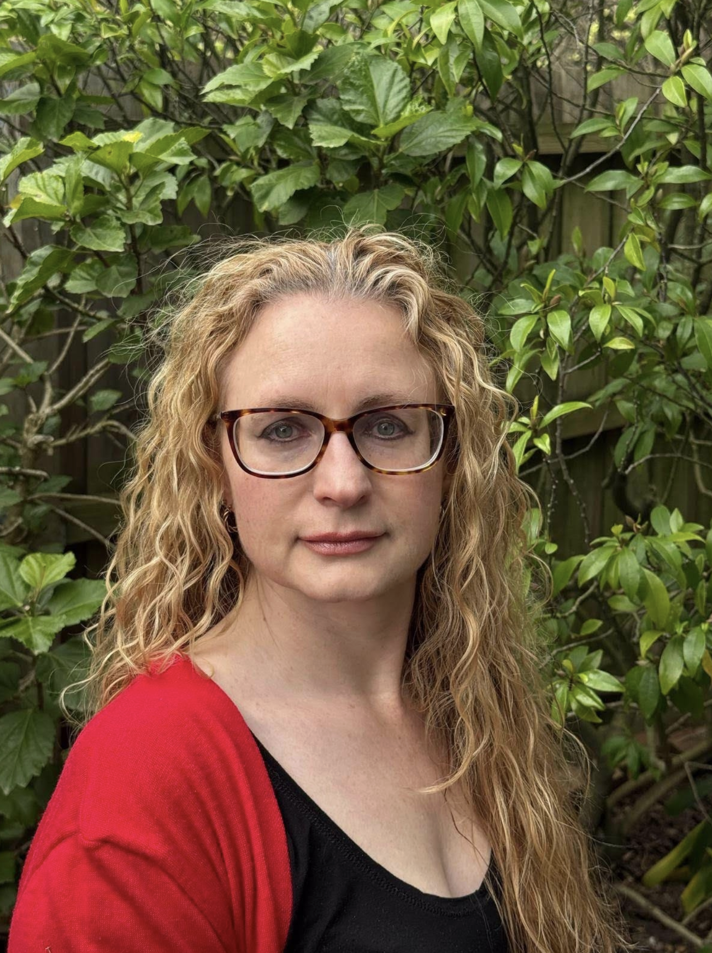 Natasha Slangen of Emotive Designs. Imagery copyright of Emotive Designs. Blonde woman with red cardigan and glasses.  