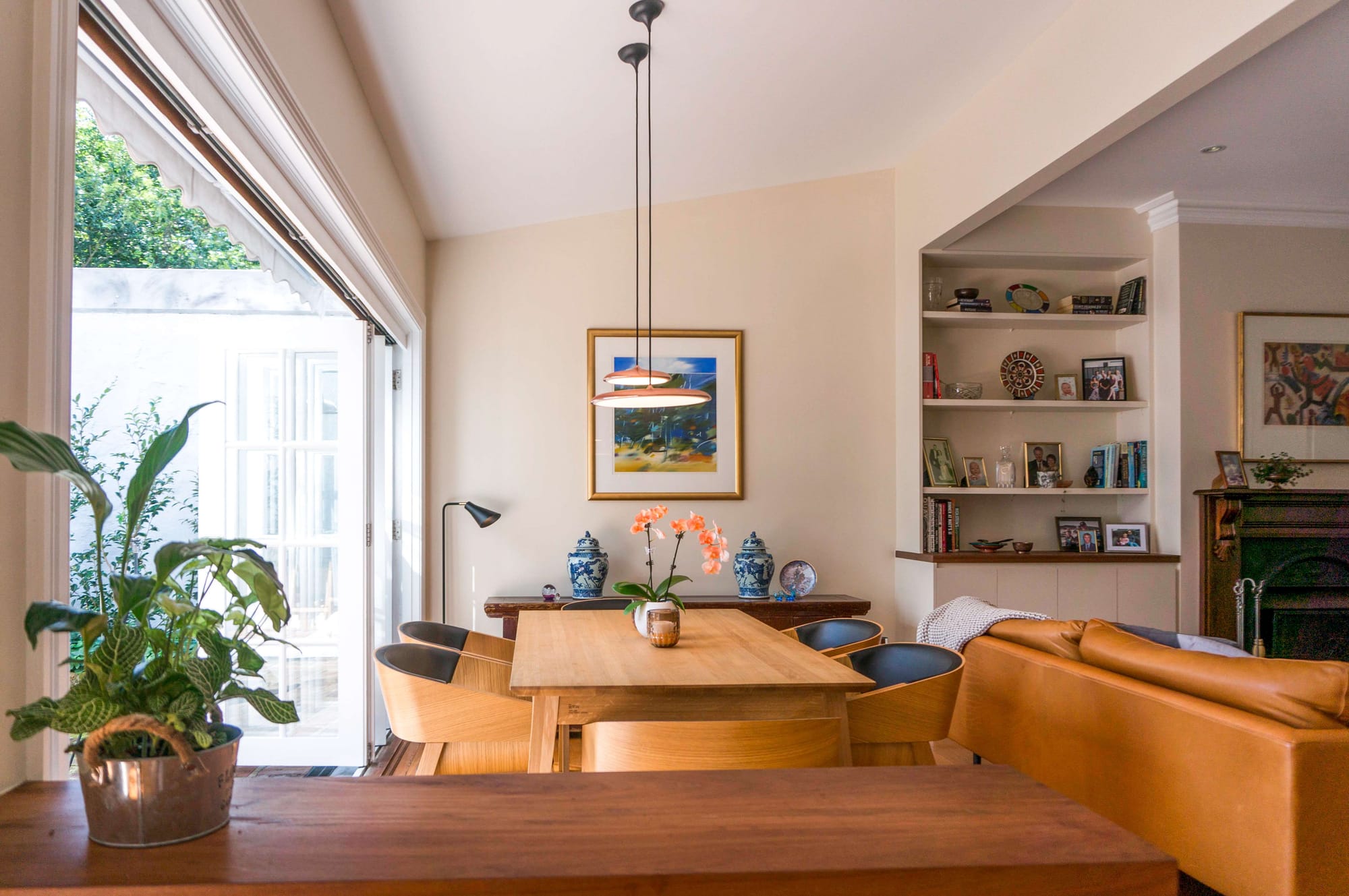 Balmain House by Nx Studio. Photograohy by Gretchen Chappelle. Open plan living and dining space with cream walls, timber table and tan leather couch. 