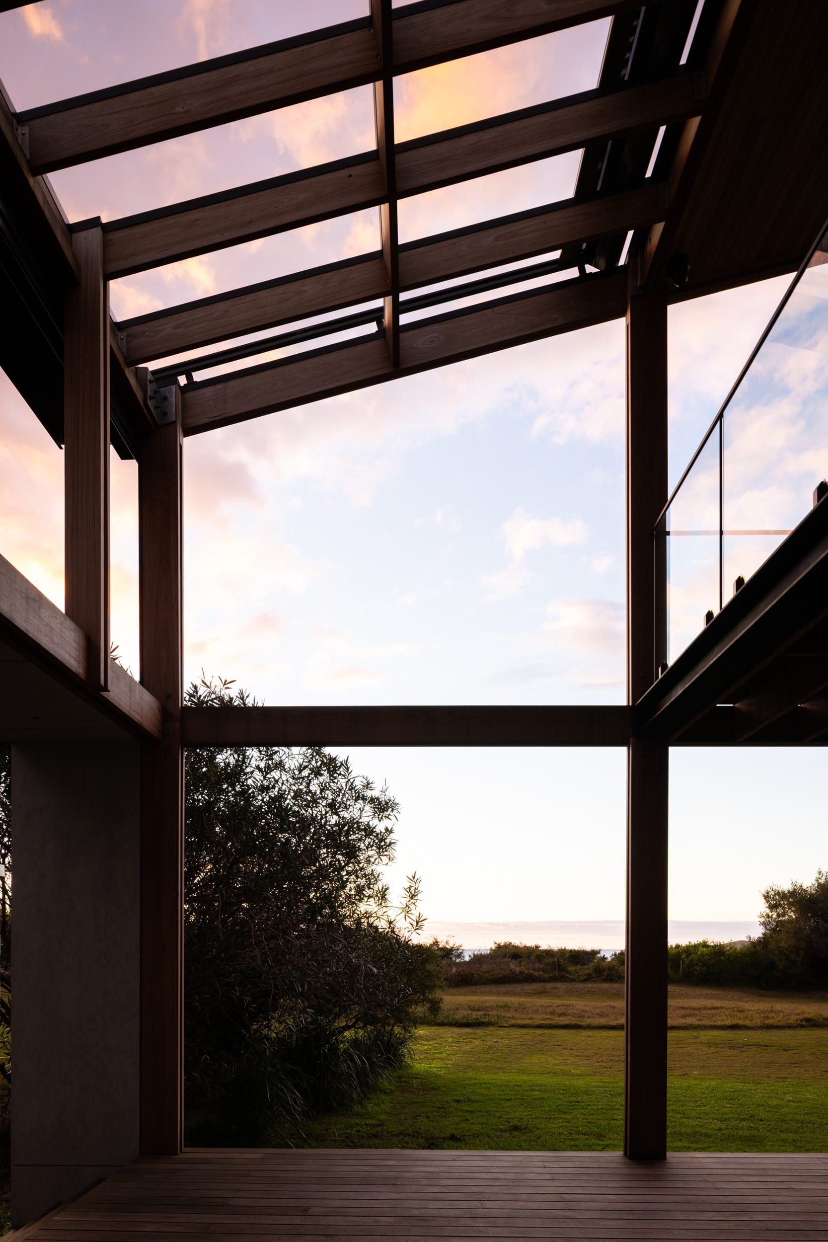 Bawley Point by Watershed Architects. Photography by Simon Whitbread. Views across timber deck, grassed foreshore and native bushland out to the ocean, at sunset. 