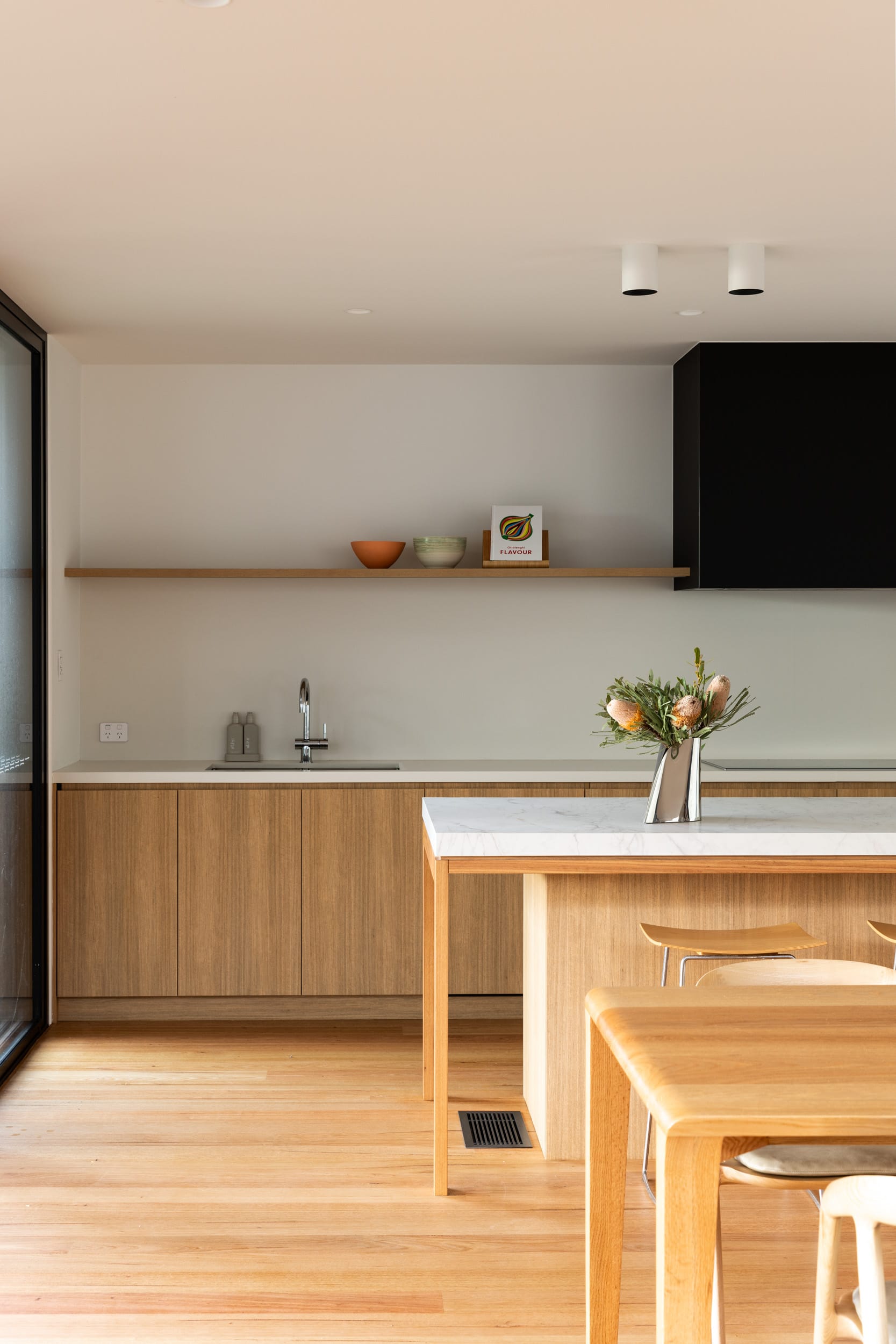 Bawley Point by Watershed Architects. Photography by Simon Whitbread. Kitchen with timber flooring, cabinets, shelving and dining table, white walls and white stone countertop. 