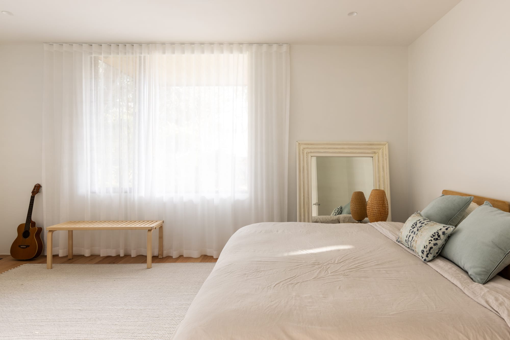 Bawley Point by Watershed Architects. Photography by Simon Whitbread. Bedroom with white walls, sheer curtains, beige rug and bed linen. 