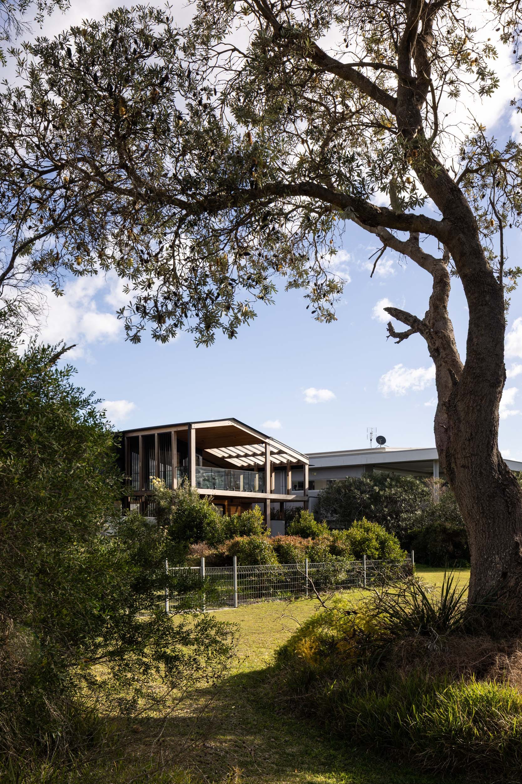 Bawley Point by Watershed Architects. Photography by Simon Whitbread. Rear facade of double-storey home backing onto grassed foreshore, dense with native flora. 
