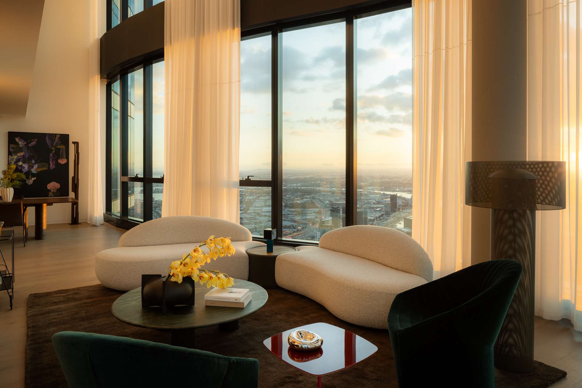 Cloud Residence by FURNISHD. Photography by Dylan James. Living space with boucle white lounges, brown rug and full height glass windows overlooking city. 