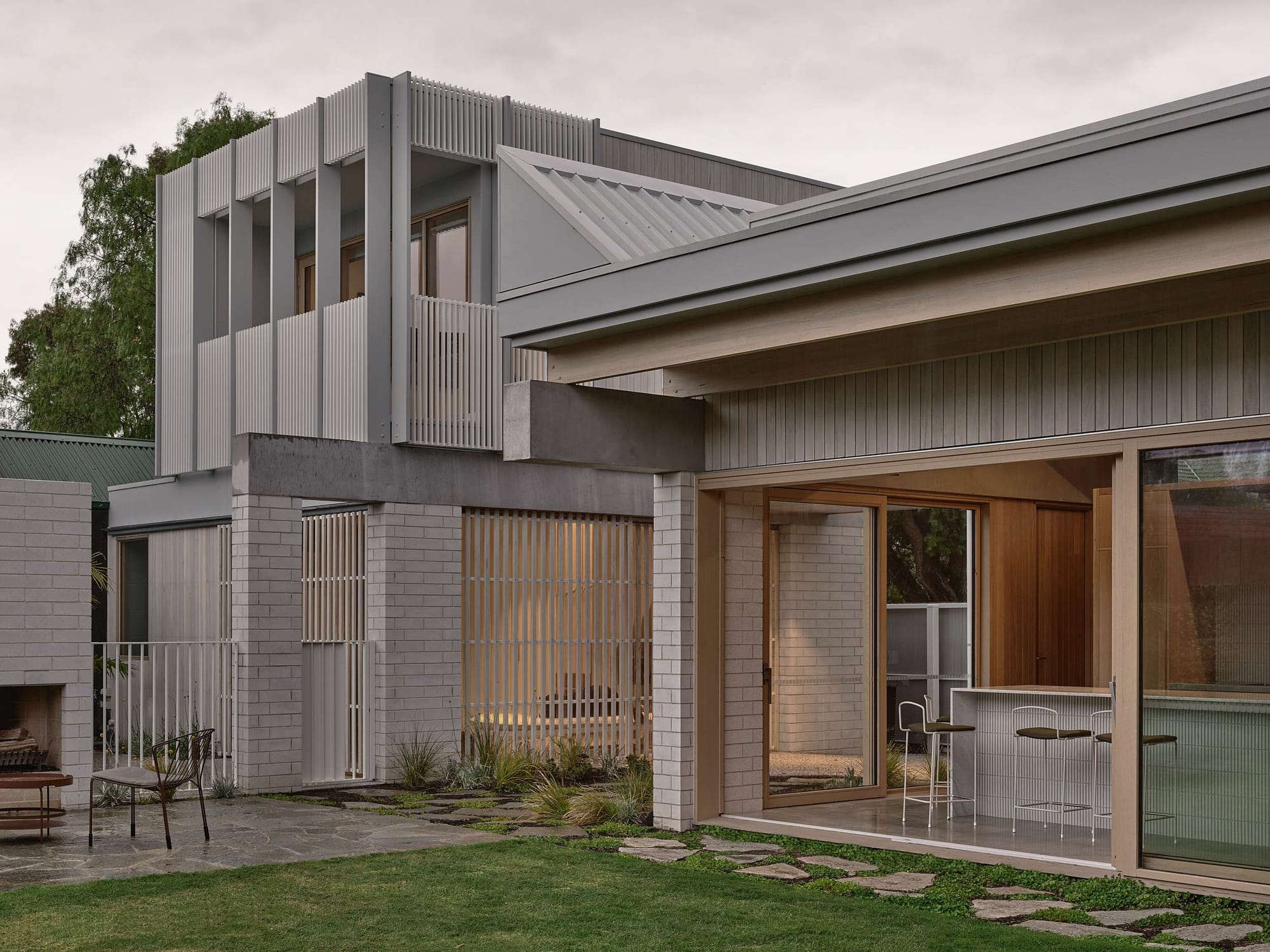 Home Pavilion by MRTN Architects. Exterior facade of home with brick, concrete and timber finish, with single level to the right and double storey volume to the left. 