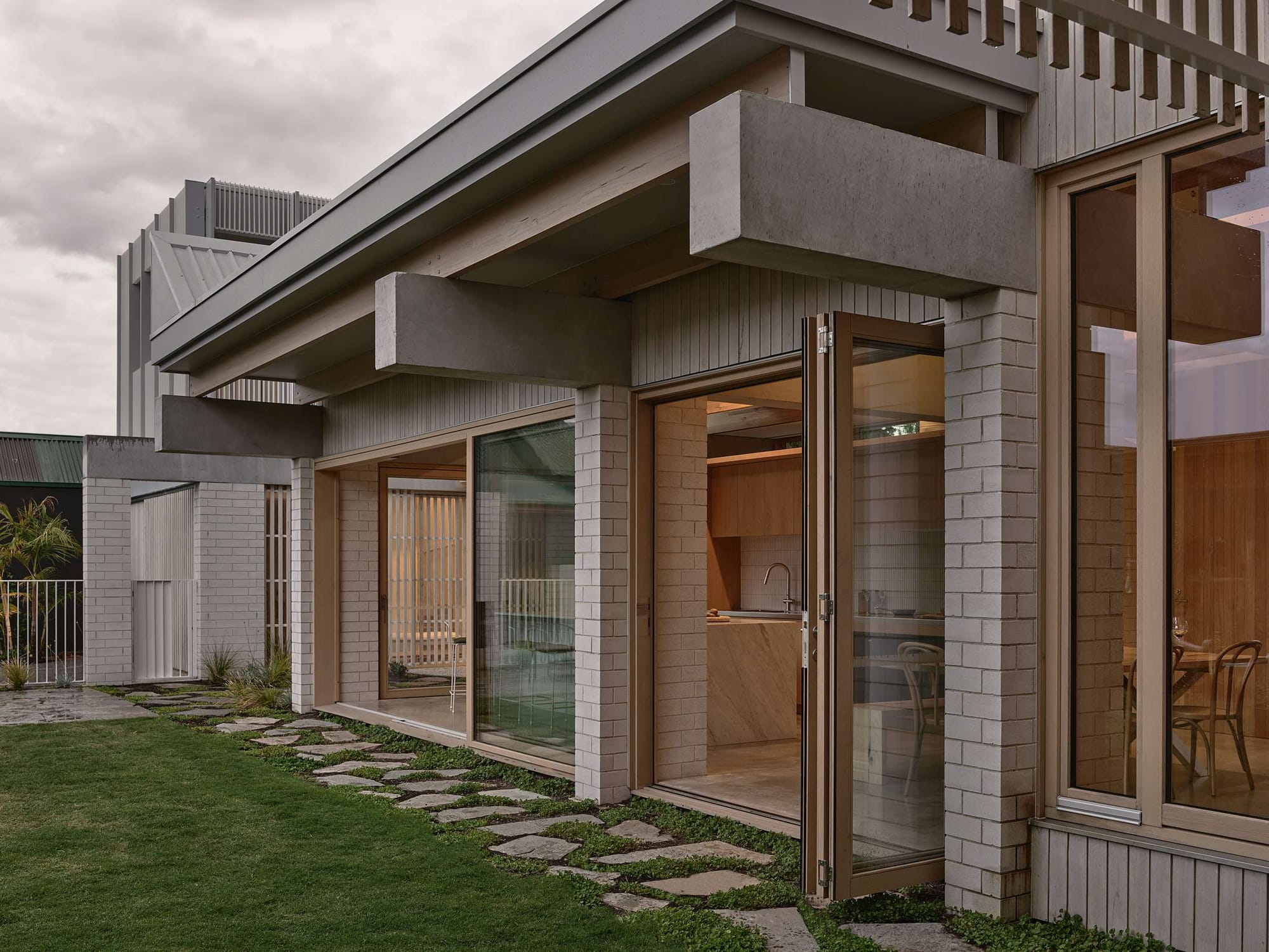 Home Pavilion by MRTN Architects. Pavilion home with brick and concrete facade, and large timber framed glass doors open onto grass courtyard. 