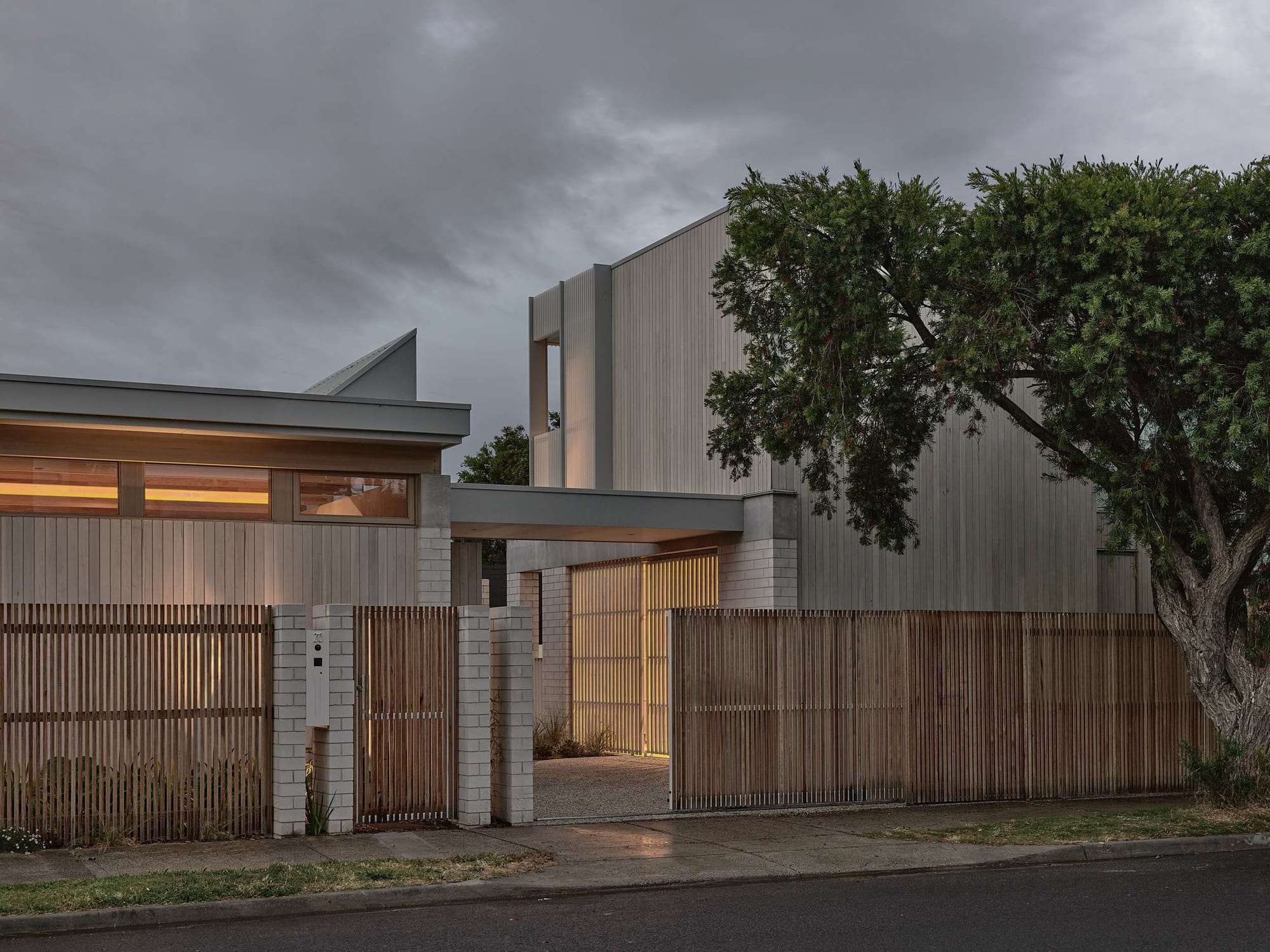 Home Pavilion by MRTN Architects. Front of home facing street, with timber, brick and concrete facade and timber fencing. 