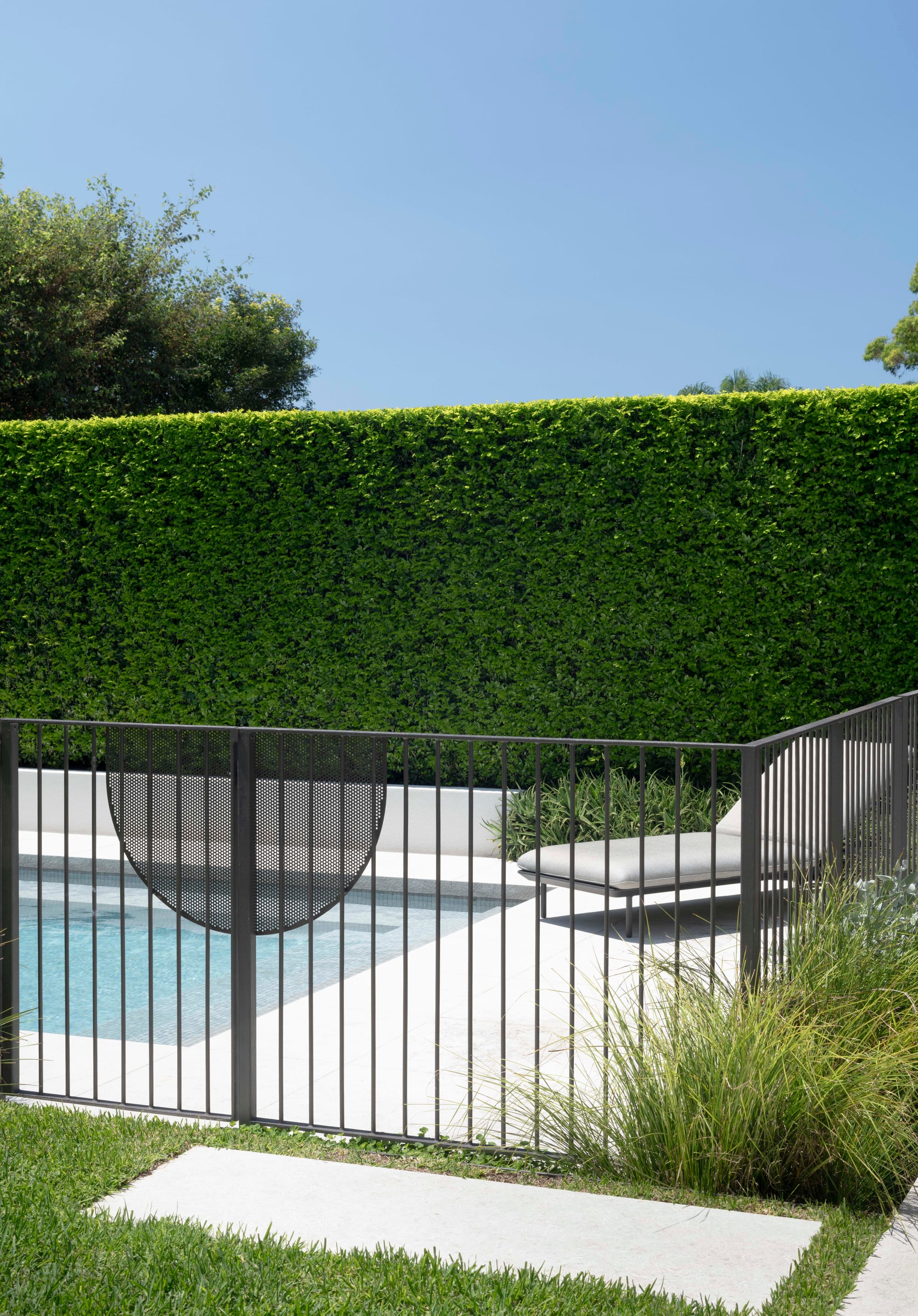 Pool area with hedges and grey deck chair