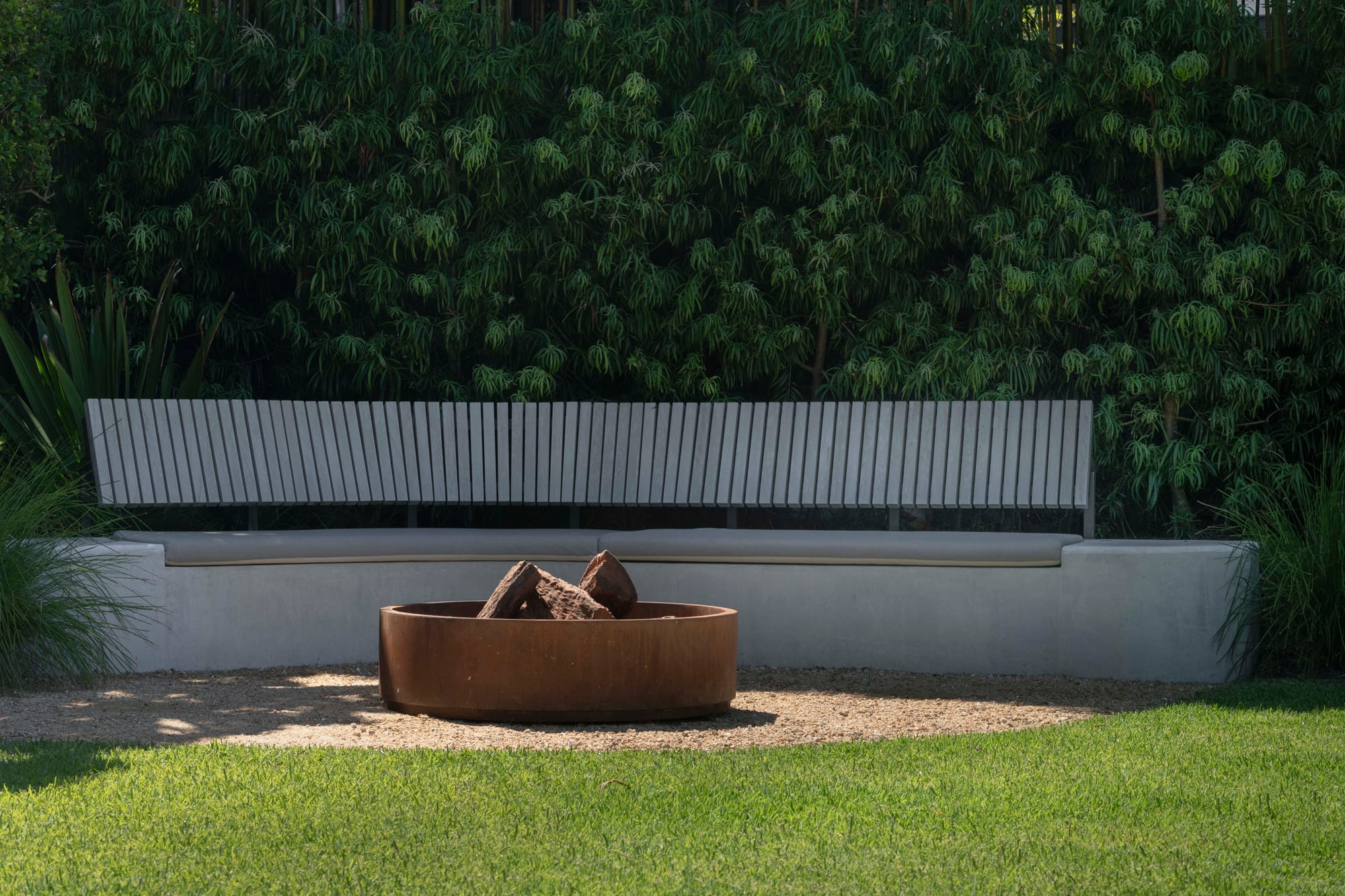 Fire pit with grey sitting area and hedges.