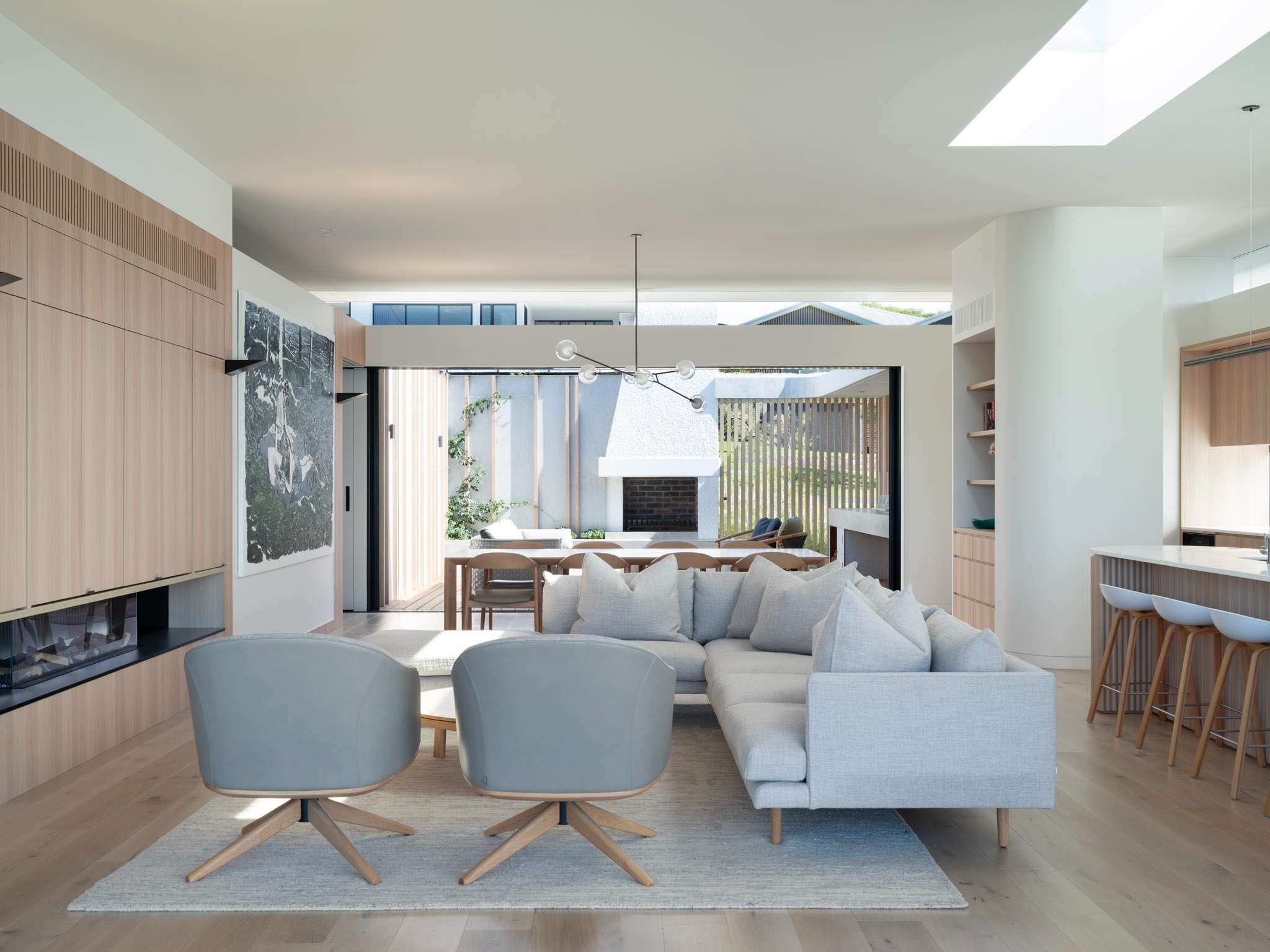 Sirius by Castlepeake Architects. Photographed by Tom Fergurson. Living area with grey couch. Wooden cabinets and wooden floor. white walls and grey carpet.