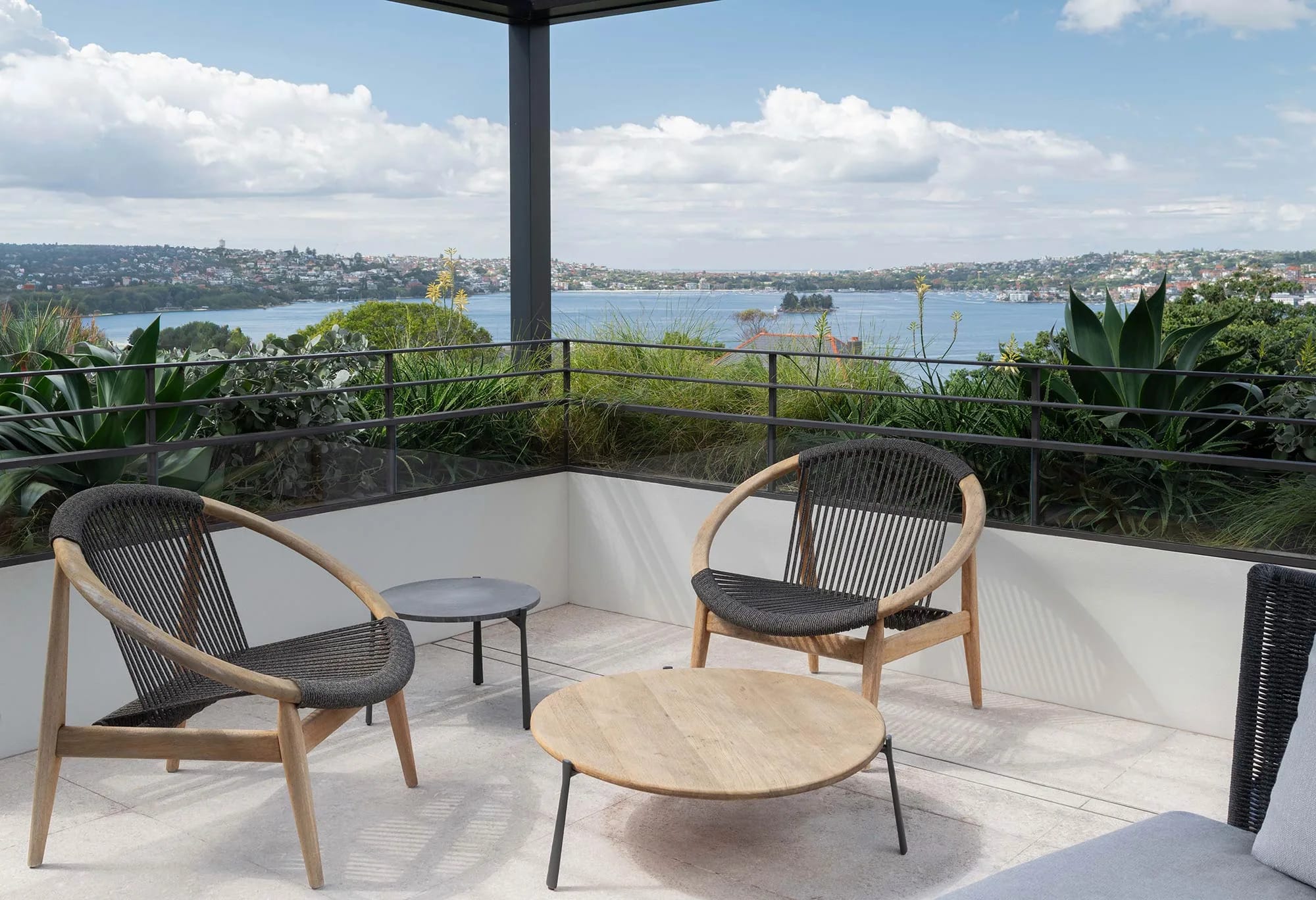 Balcony, rooftop with coastal view. wooden outdoor chairs and outdoor coffee table.