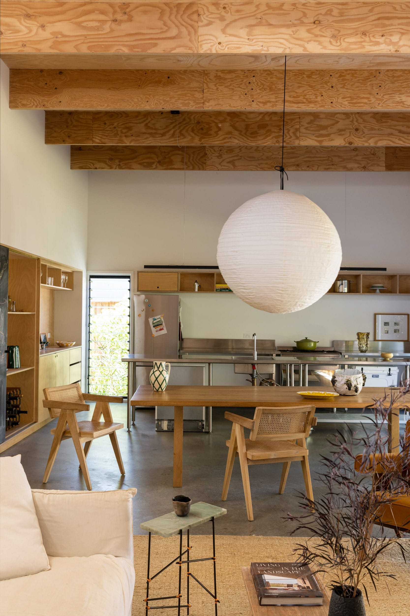 Drip-Dry House by Marker Architecture & Design. Photographed by Simon Whitbread. Kitchen with metal kitchen bench. Japanese orb pendant lamp. dinning area with wooden cabinets