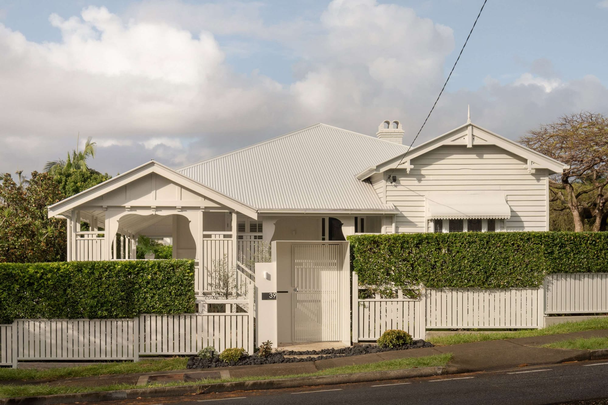 Classic Queenslander-style home exterior with white weatherboards and picket fence, restored through heritage Brisbane renovations