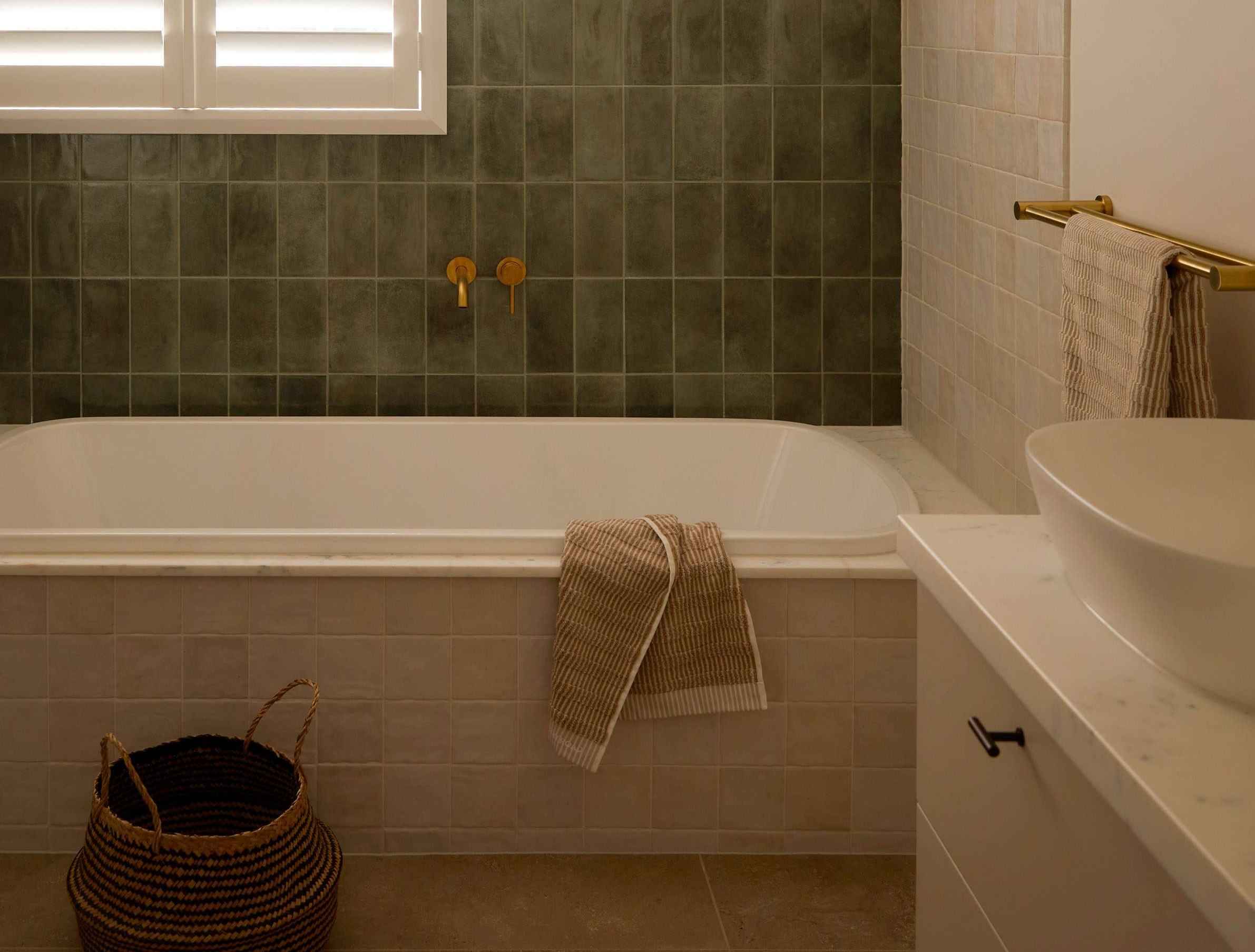 Warm, tiled bathroom with built-in bathtub, brass fixtures, and soft lighting, part of a modern Melbourne renovation