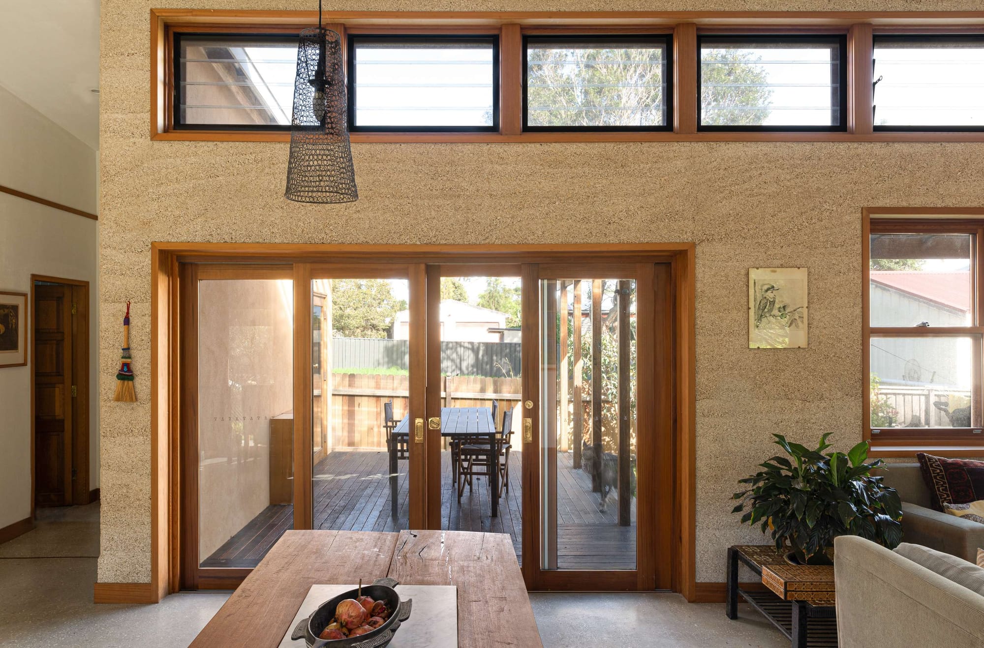 Textured interior living space with timber-framed glass doors opening to a deck, featured in a sustainable home renovation in Sydney