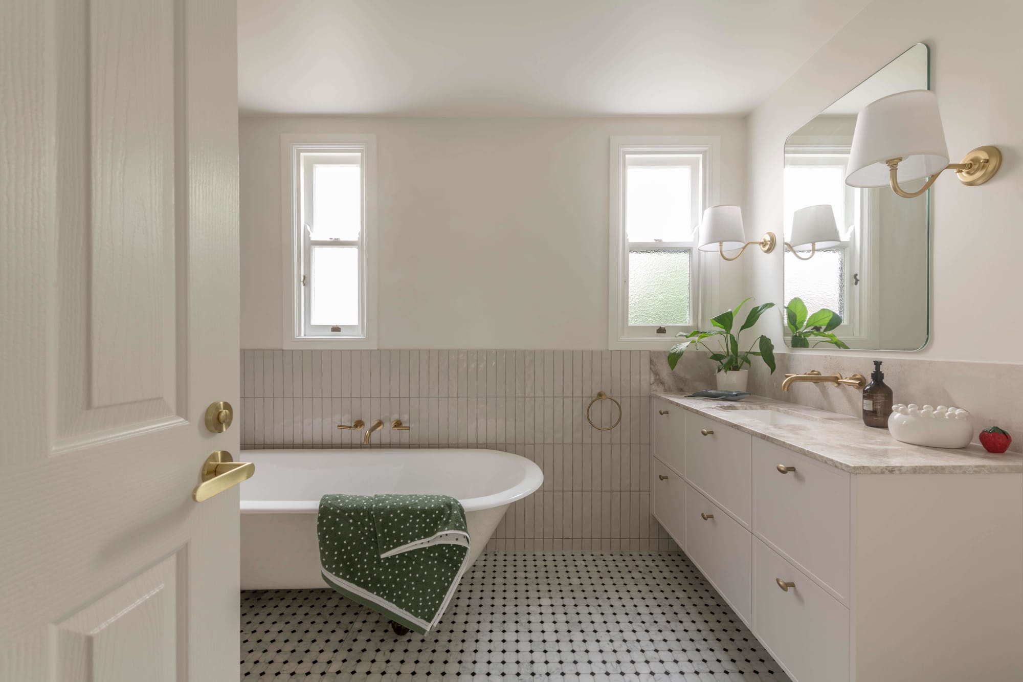 Bright bathroom with freestanding bathtub, marble vanity, and brass fixtures, highlighting elegant Brisbane renovations