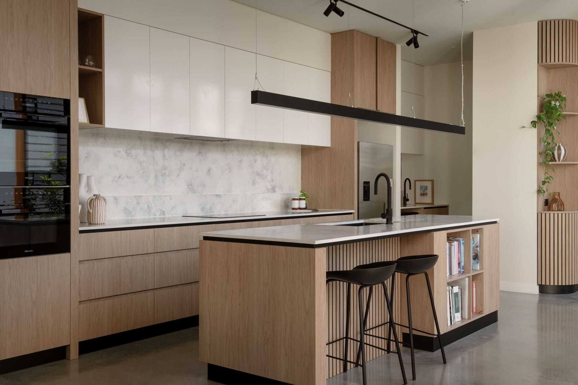Modern kitchen with timber cabinetry, white overhead cupboards, and island bench, featured in stylish Brisbane renovations