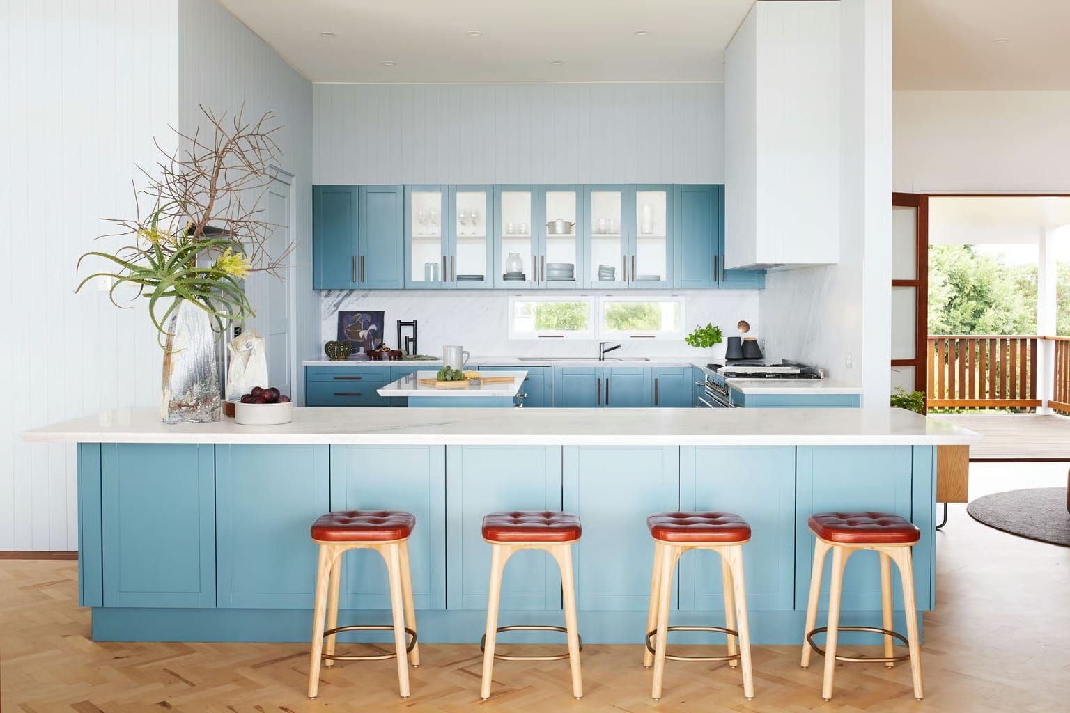 Bright blue kitchen with island bench and timber stools, part of a modern home renovation in Sydney