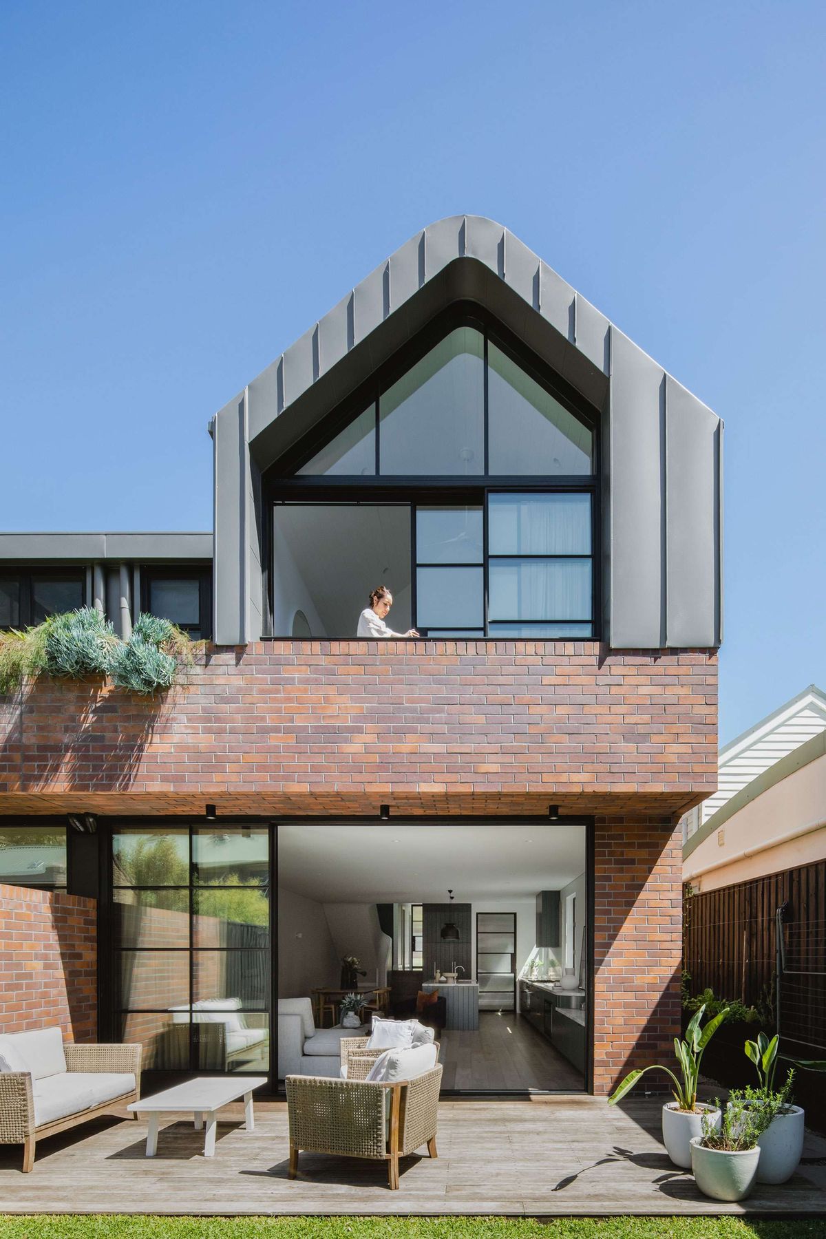 Dulwich Hill Duo by Blake Letnic Architects showing rear elevation of the brick house and a timber deck with outdoor furnitu
