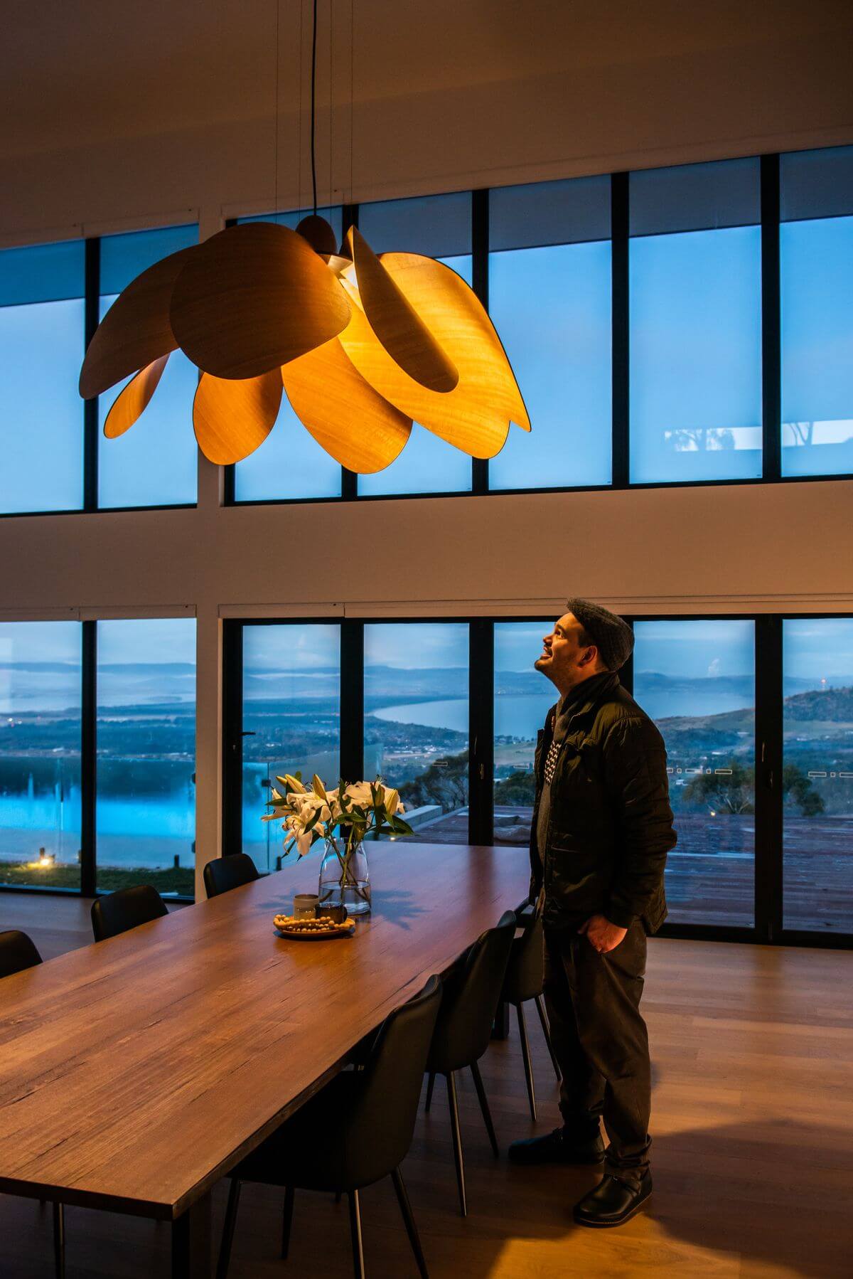 Duncan Meerding standing looking up at his Propeller Bloom installed in a dining space
