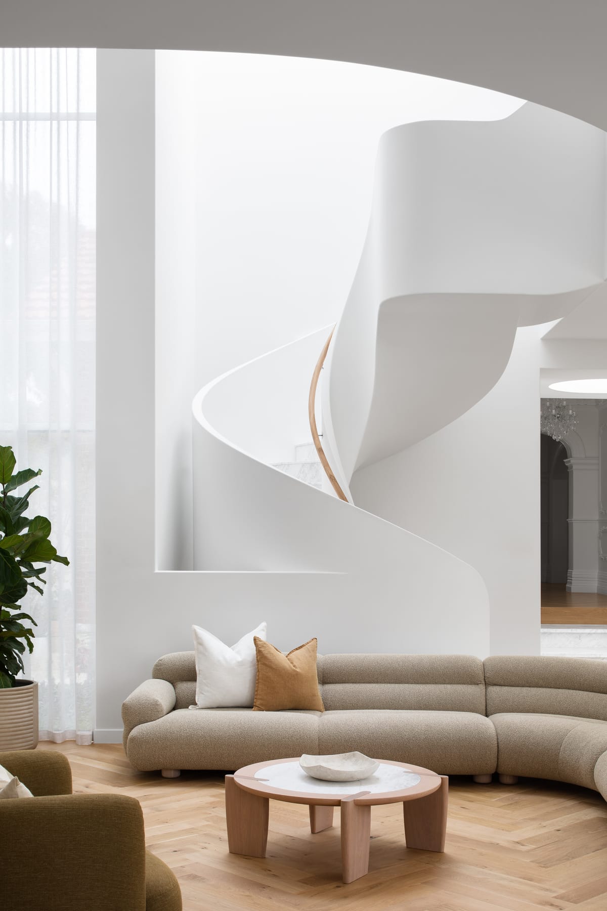 The Grove by Taouk Architects. Living room with curved seating in foreground spiral staircase in backgroun